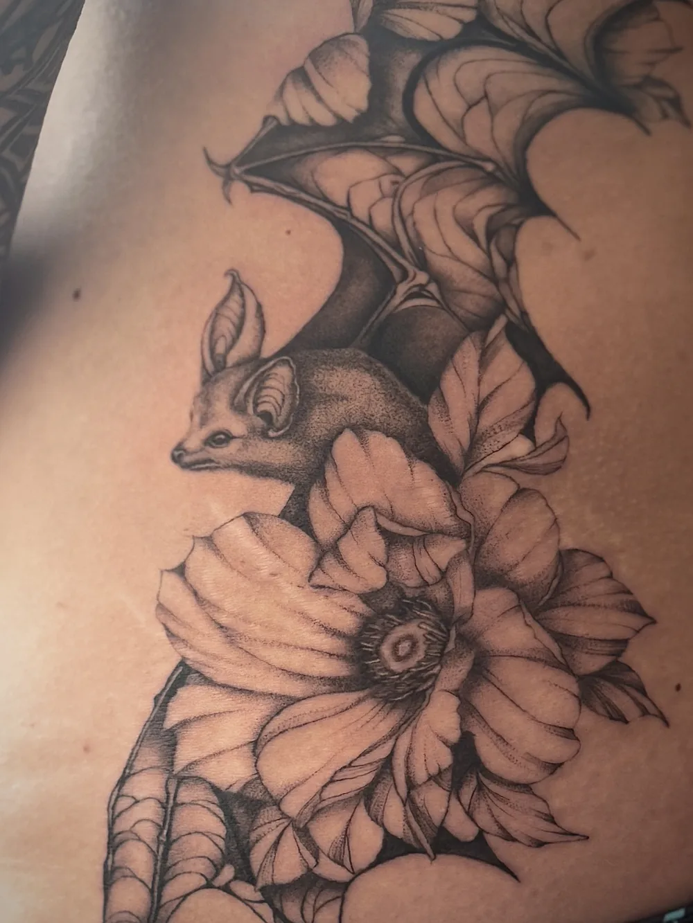 Tattoo mit Fledermaus und Blüten in einer Nahaufnahme