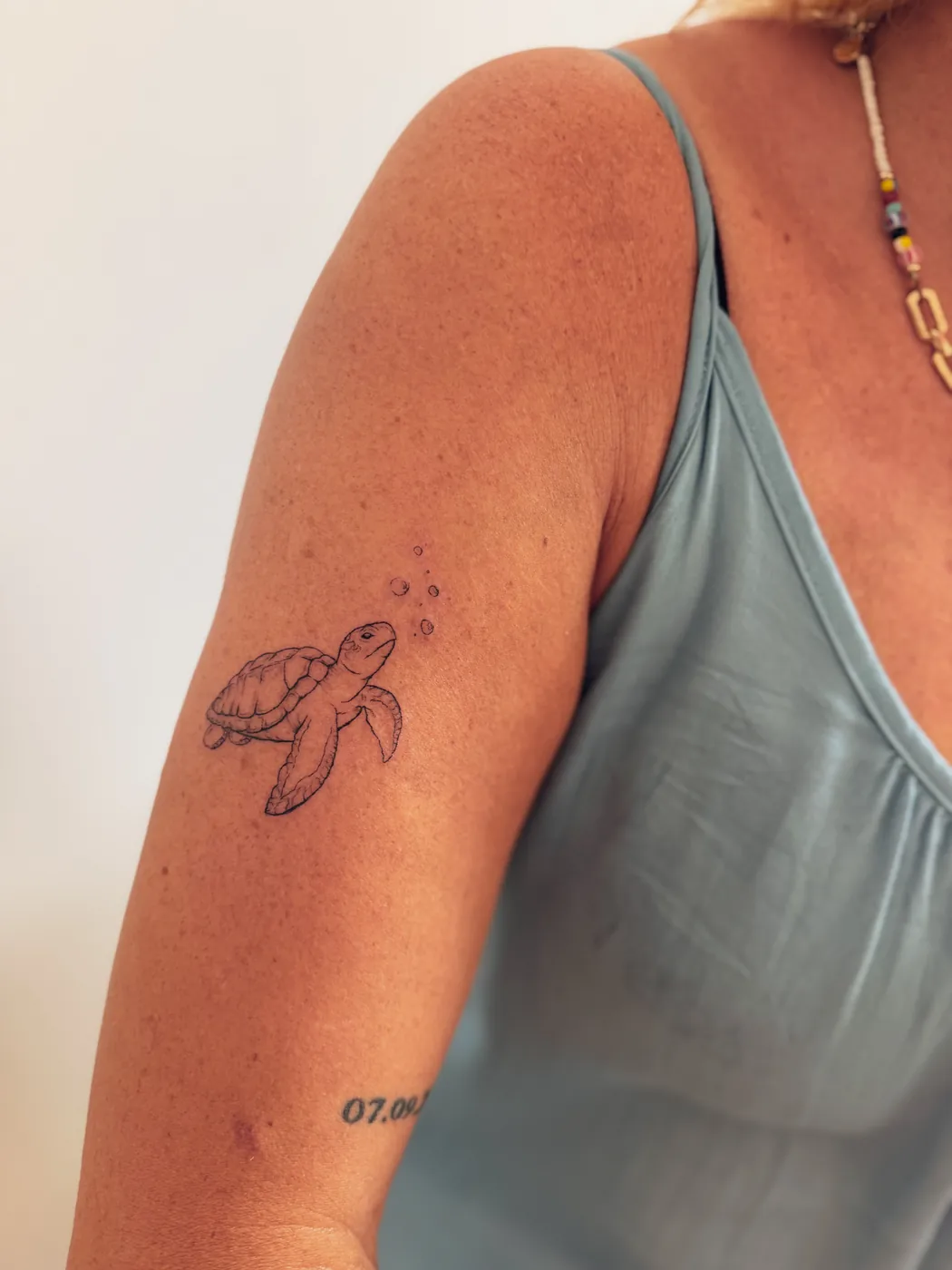 Kleine Schildkröte als Tattoo auf einem Oberarm